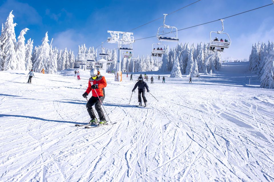 Skifahrer auf einer schneereichen Piste schlittern den Abhang herunter.